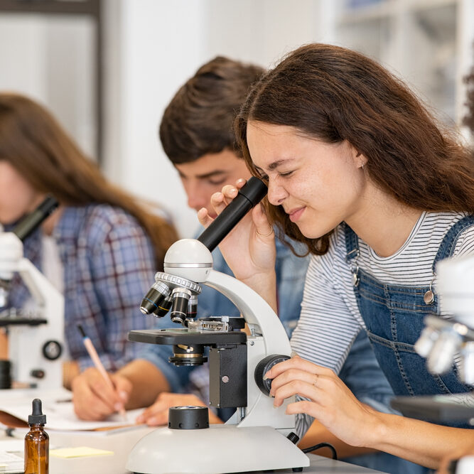 Group,Of,College,Students,Performing,Experiment,Using,Microscope,In,Science