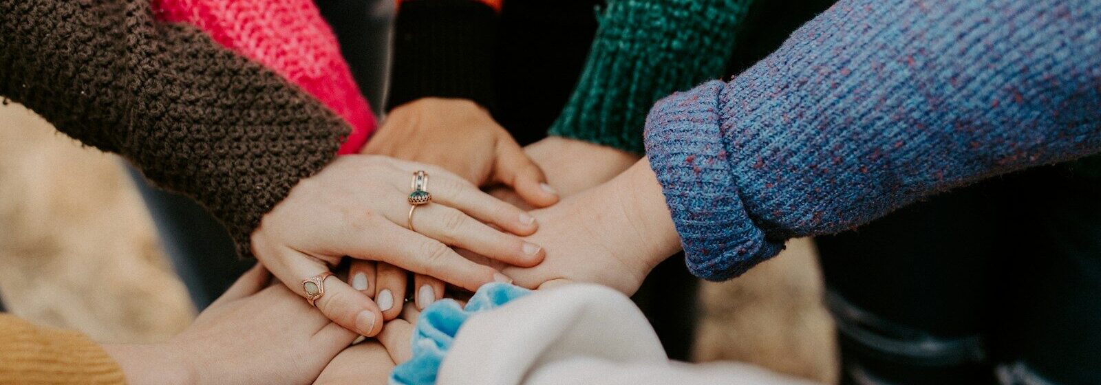 group stacking hands in colorful sweaters