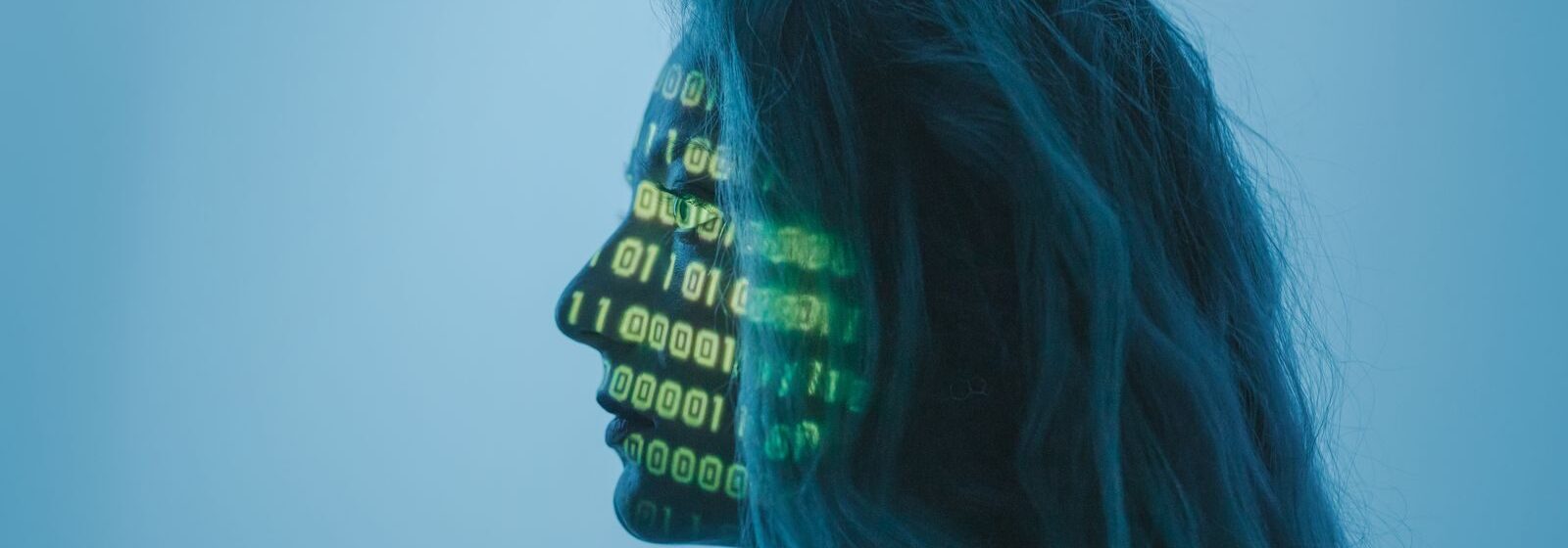 Silhouette of a woman with binary code projected on her face in a digital concept setting.