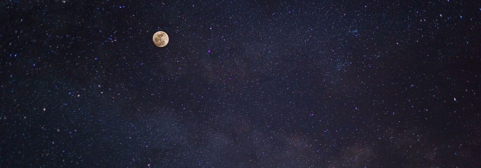 A breathtaking view of the full moon against a starry night sky with the Milky Way.